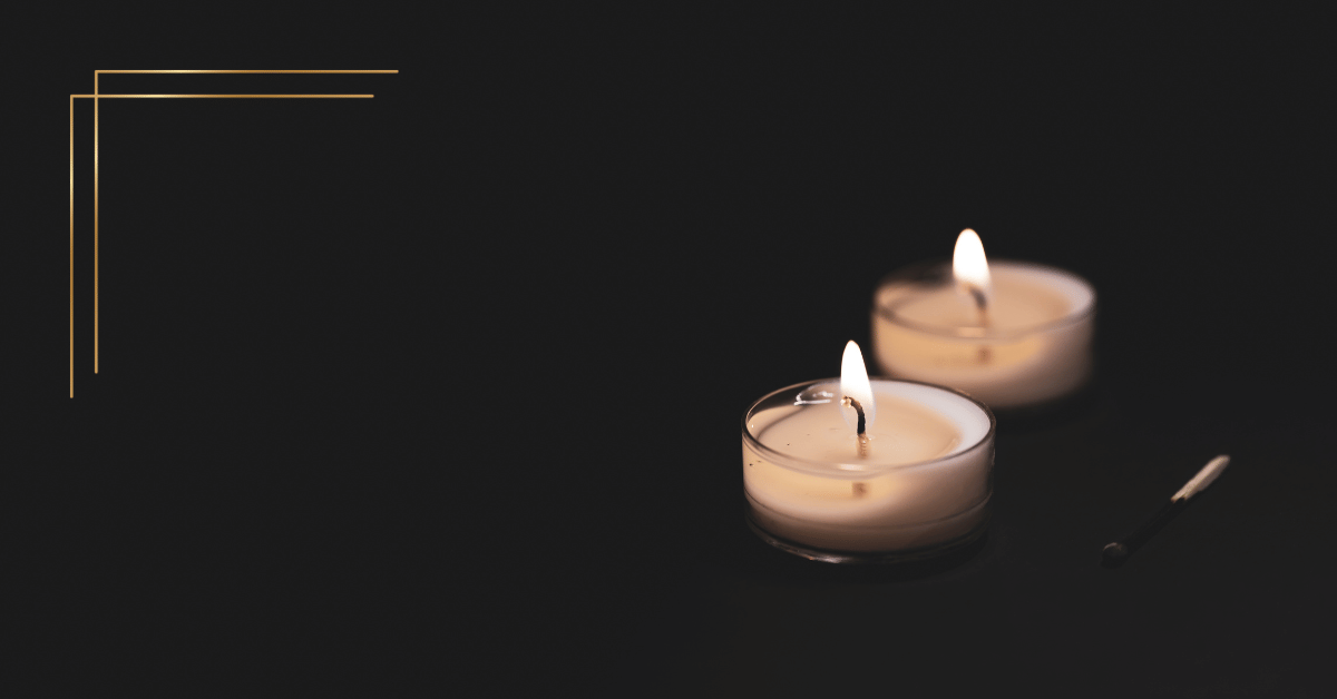 Image shows a black background with two tea light candles lit in the bottom right hand corner